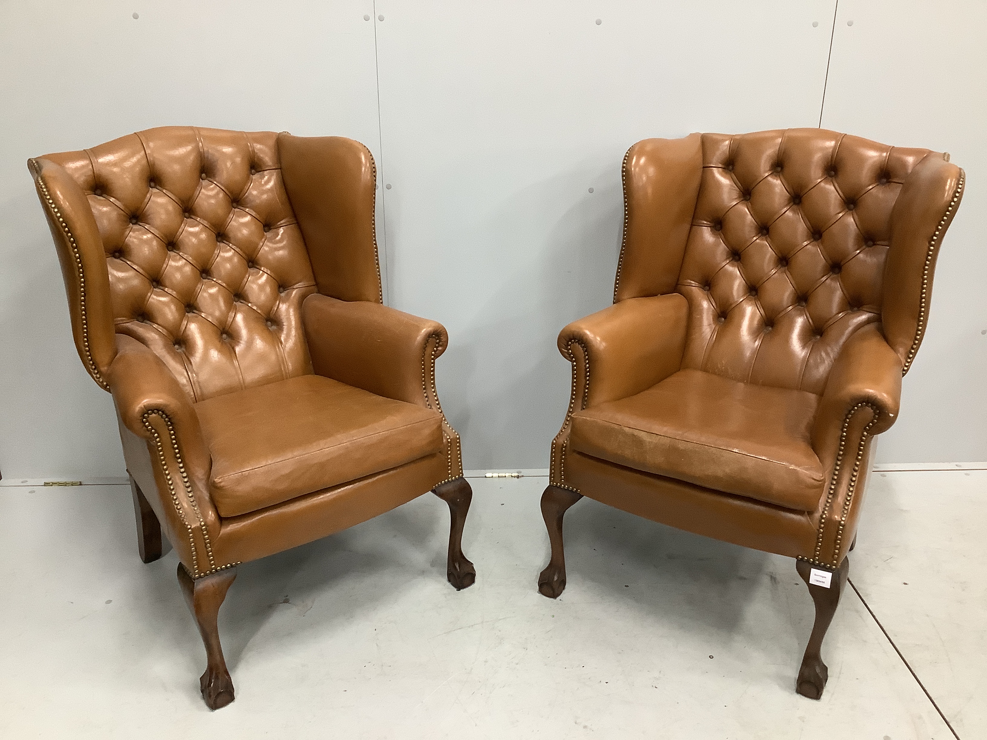 A pair of reproduction George III style buttoned pale brown leather wing armchairs, width 75cm, depth 66cm, height 107cm